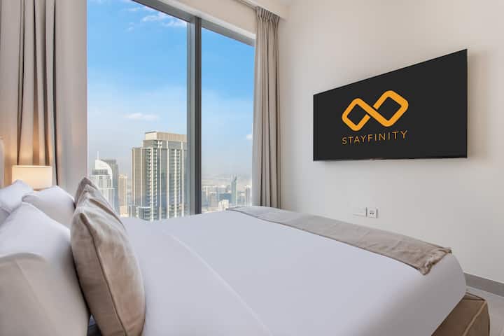 Un lit king size avec une télévision connectée et une vue imprenable sur la ville depuis le 65e étage. Les fenêtres du sol au plafond laissent entrer la lumière naturelle et les rideaux occultants assurent une nuit de sommeil paisible dans cet espace luxueux et moderne.