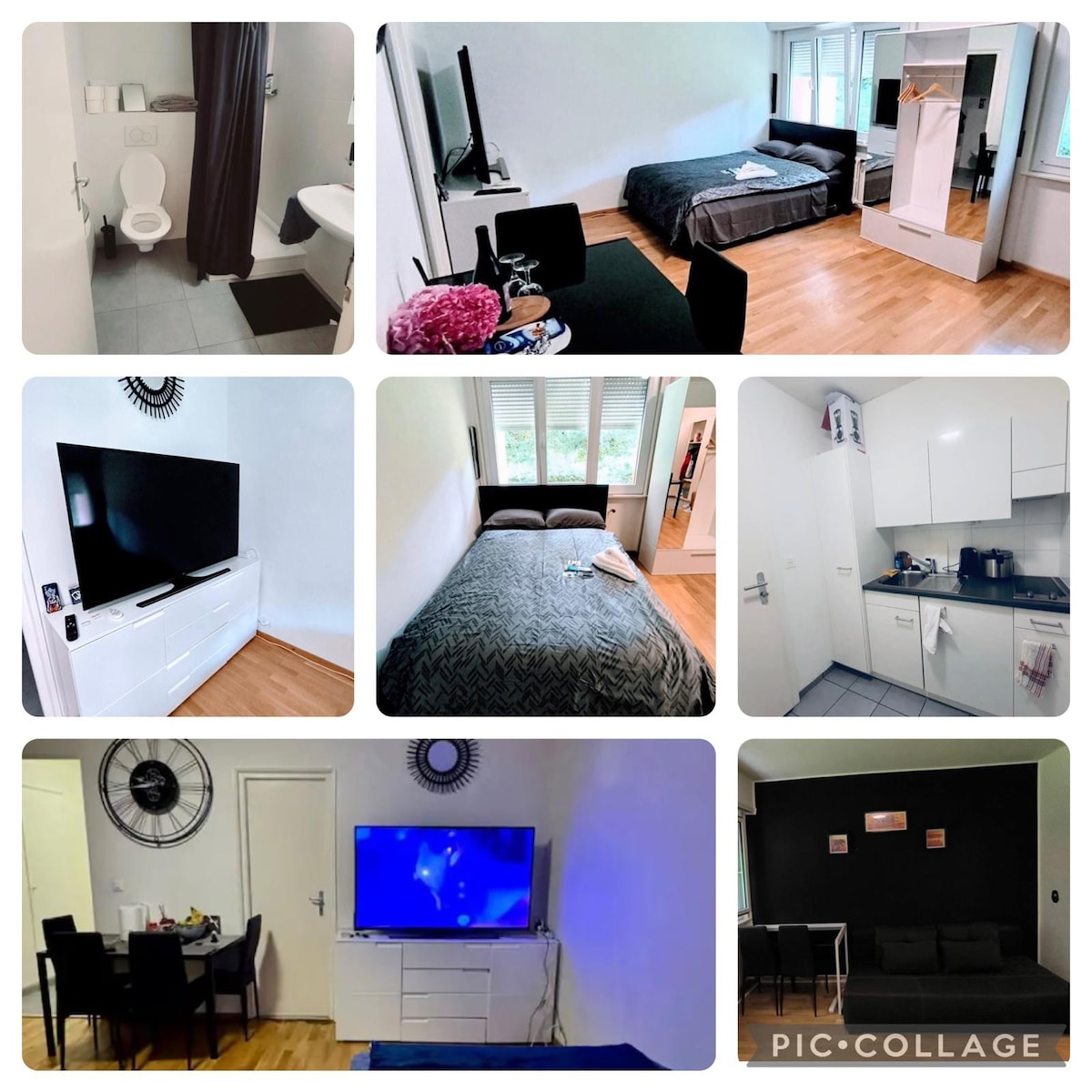 A modern bathroom is featured with a clean white toilet and tiled flooring. The bedroom contains a spacious bed with a gray coverlet, complemented by natural light from large windows. A sleek entertainment unit holds a flat-screen TV, and a dining area includes a table and chairs.