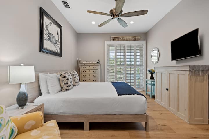 King bedroom and balcony with partial view of beach.