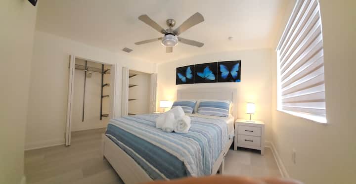 חדר שינה עם מיטת קווין סייז, סדיני משי וטלוויזיה חכמה ROKU בגודל 42אינץ '.