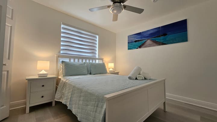 חדר שינה עם מיטת קווין סייז, סדיני משי וטלוויזיה חכמה ROKU בגודל 42אינץ '.