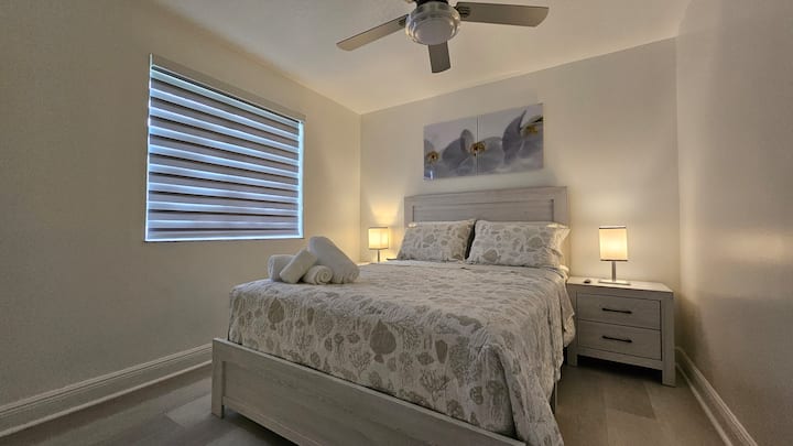 חדר שינה עם מיטת קווין סייז, סדיני משי וטלוויזיה חכמה ROKU בגודל 42אינץ '.