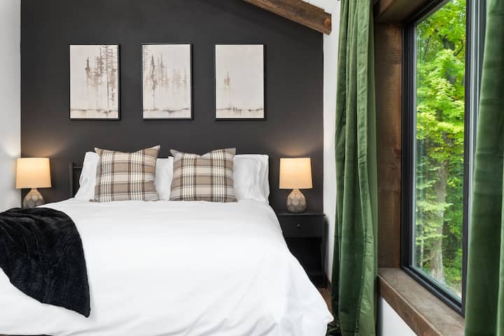 Charming secondary bedroom featuring a queen-sized bed, plush white bedding, additional pillows, blackout curtains, comfy blankets and a soothing sound machine.
