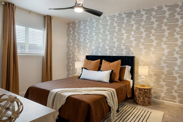 Enjoy a restful night's sleep in this beautifully decorated bedroom with stylish wallpaper and cozy bedding. The ceiling fan provides added comfort.
