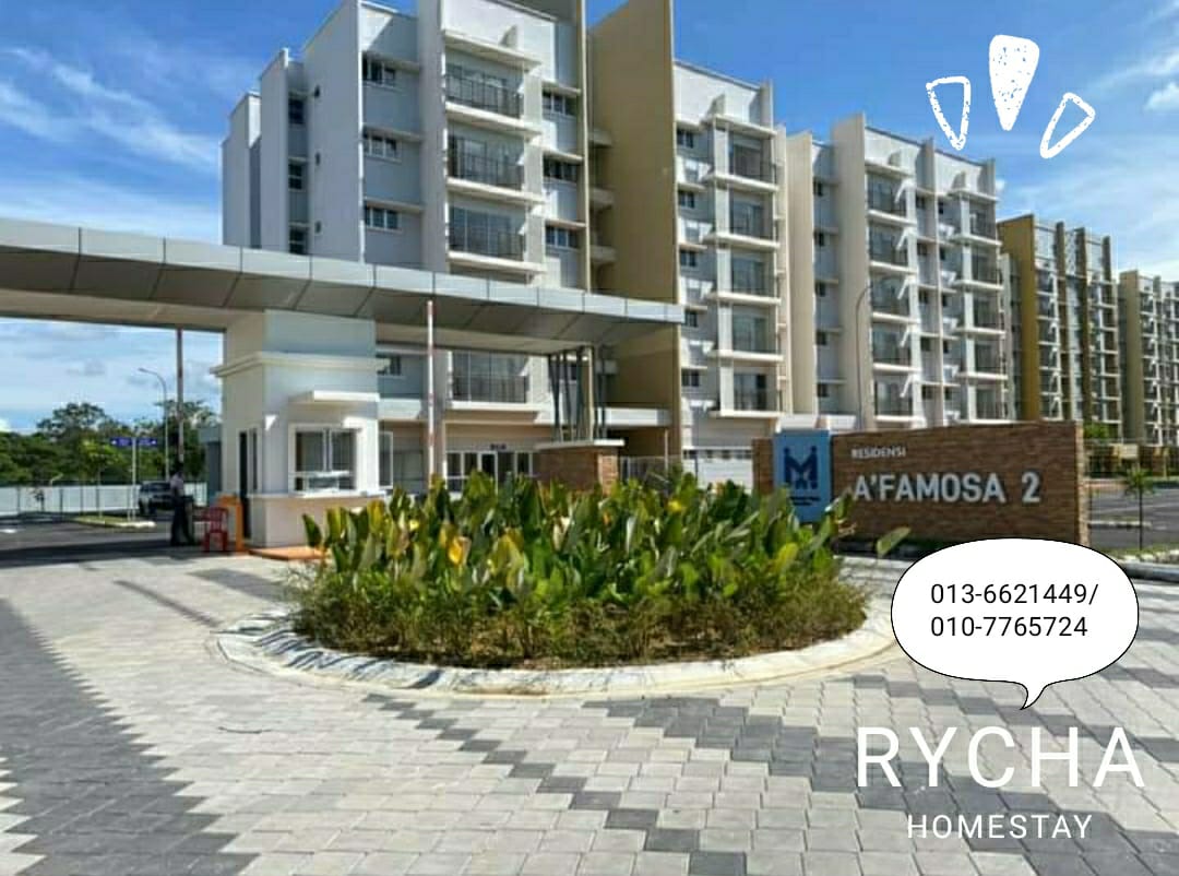 An urban apartment complex is depicted, featuring a modern façade with multiple levels. A landscaped area with green plants is showcased in the foreground. Paved walkways provide access to the entrance, which is marked with a stone sign displaying the building's name.