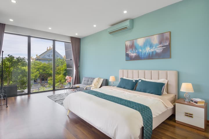 Cuarto dormitorio con una cómoda cama tamaño king, un sofá cama y una enorme ventana en el este, y acceso directo a la terraza con equipo de gimnasio.