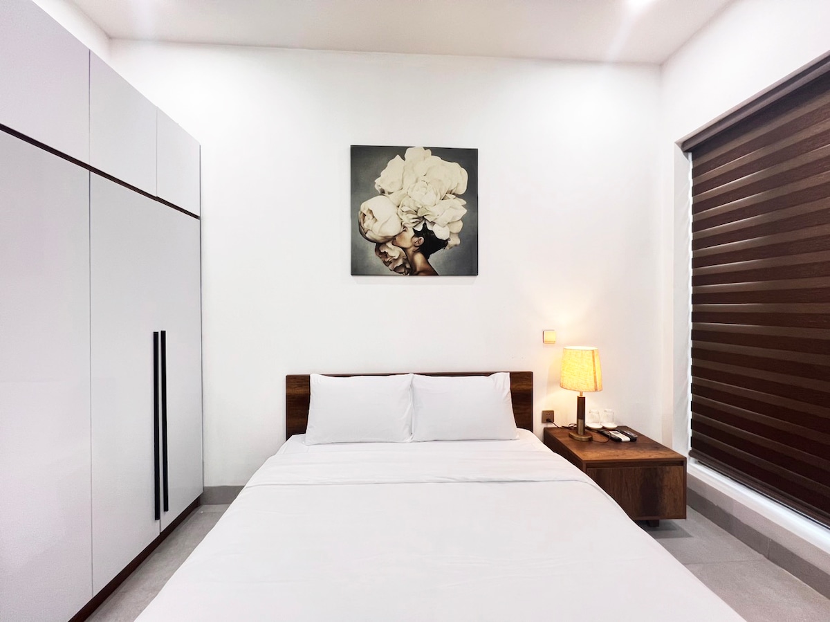 Spálňa 101 v Sophia Villa ponúka útulný, minimalistický dizajn s manželskou posteľou, mäkkým osvetlením a priestrannou šatníkovou skriňou. Neutrálne tóny a štýlové umelecké diela vytvárajú pohodlnú a pokojnú atmosféru ideálnu na pokojný nočný spánok.
