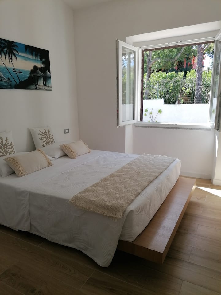 Camera matrimoniale con affaccio nell'oasi verde che circonda la villa per un risveglio con il profumo degli agrumi e delle erbe tipiche della macchia mediterranea che si fonde con quello dell'aria salmastra.