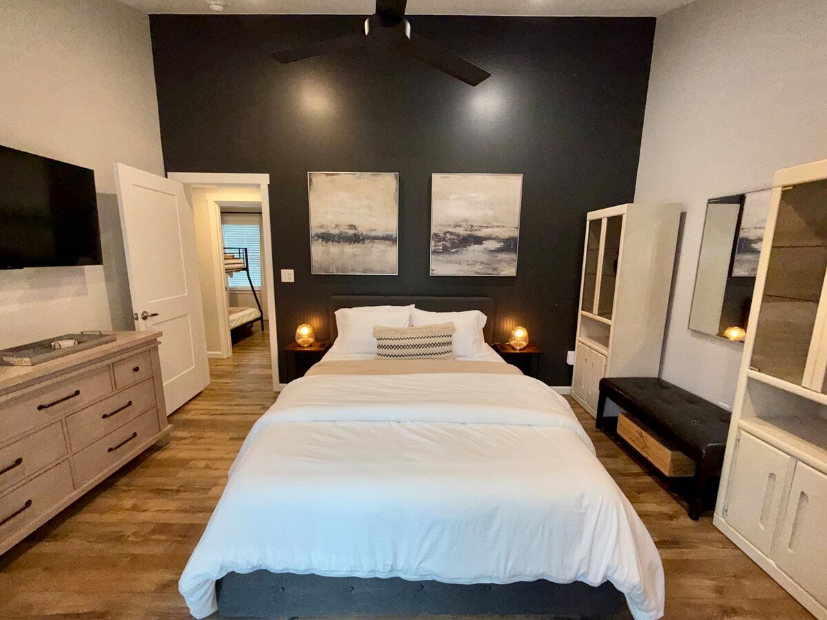 החדר הראשי: כולל מיטת קווין סייז עם מצעים לבנים נקיים. תאורה רכה של מנורות ליד המיטה יוצרת אווירה שלווה, מושלמת להירגעות. בחדר הזה יש חדר רחצה פרטי וגישה לדק, מקלחת חיצונית וחצר אחורית דרך דלת הזזה.