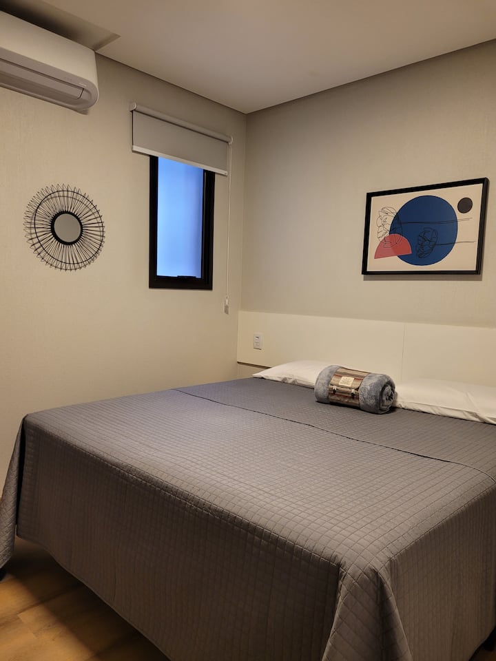 Studio 201 com o quarto arrumado com cama para casal (medida entre cama queen e king).