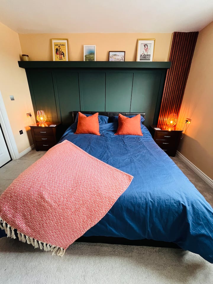 Relájate en este acogedor y elegante dormitorio principal con una cama tamaño king, obras de arte enmarcadas de todo el mundo e iluminación cálida para una noche de sueño sereno y cómodo.