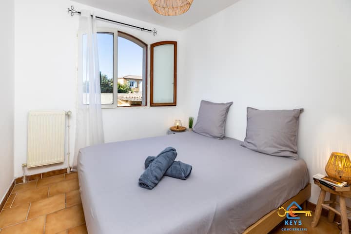 Het comfortabele tweepersoonsbed, badend in natuurlijk licht, nodigt je uit om te ontspannen. De nabijheid van het raam biedt een rustgevend uitzicht op de buitenkant, perfect voor een moment van rust.