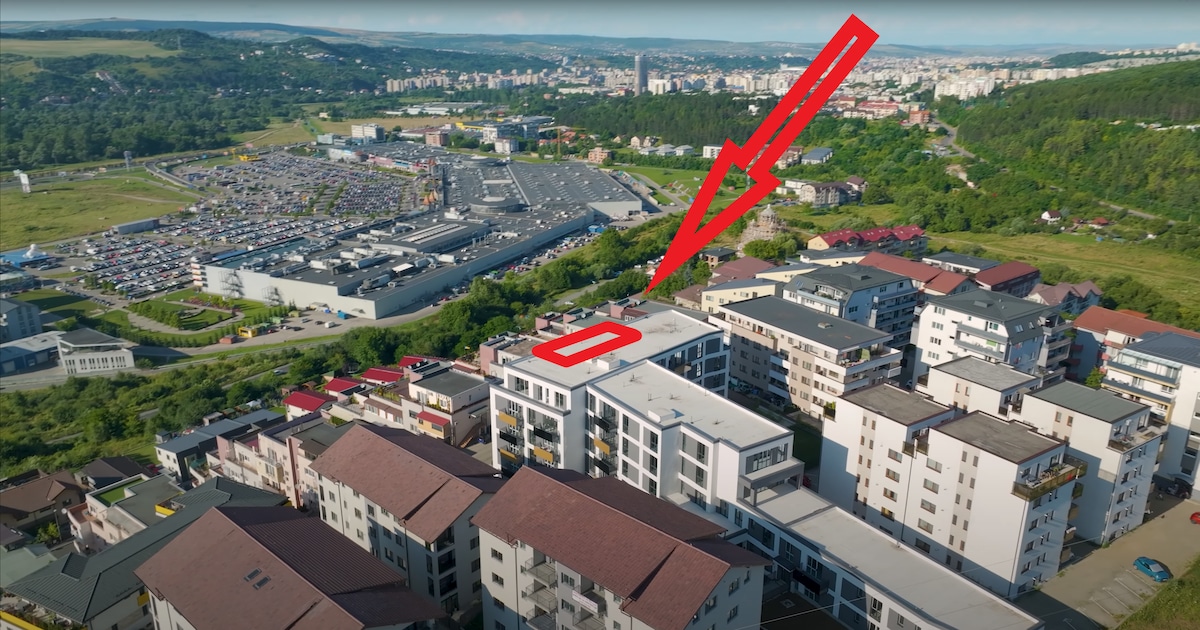 An aerial view showcases the modern penthouse situated atop the Tribeka VIVO Residence, overlooking the VIVO Mall and surrounding landscapes. The complex is surrounded by lush greenery, with a panoramic view of the nearby urban area and expansive parking facilities.