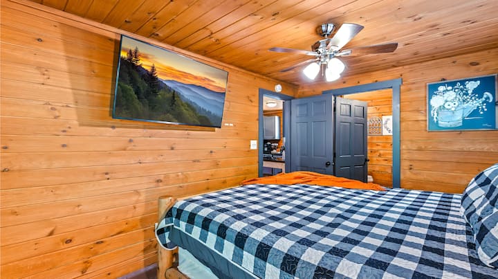 Užite si rustikálny šarm spálne 1 v Adventure A Beach s pohodlnou posteľou s útulným hodom, stropným ventilátorom a televízorom s scenériou Smoky Mountain. Perfektné útočisko na oddych!