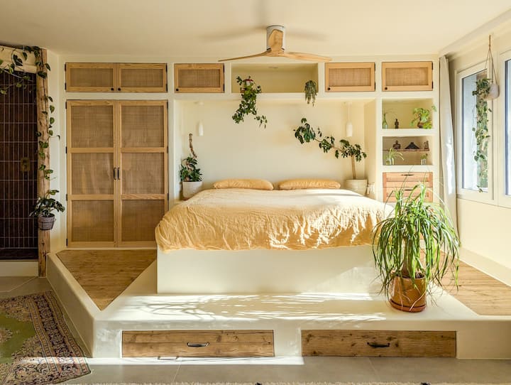 ಬೆಳಗಿನ ಬೆಳಕು ಮಲಗುವ ಪ್ರದೇಶವನ್ನು ತುಂಬುತ್ತದೆ, ಕಿಂಗ್-ಗಾತ್ರದ ಹಾಸಿಗೆಯನ್ನು ಅದರ ಲಿನೆನ್ ಶೀಟ್‌ಗಳಿಂದ ಹೈಲೈಟ್ ಮಾಡುತ್ತದೆ. ಸ್ಮಾರ್ಟ್ ಸೀಲಿಂಗ್ ಫ್ಯಾನ್‌ಗಳು ಹೆಚ್ಚುವರಿ ಆರಾಮಕ್ಕಾಗಿ ರಿಫ್ರೆಶ್ ತಂಗಾಳಿಯನ್ನು ಒದಗಿಸುತ್ತವೆ.