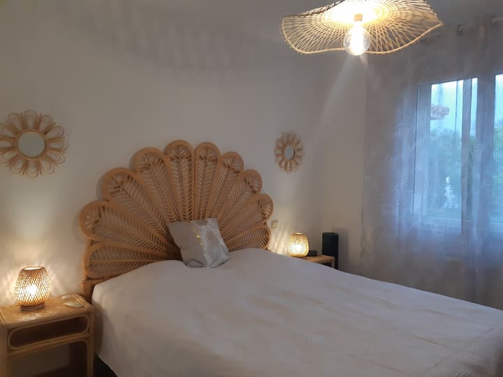 Chambre 1 à l'ameublement exotique en bambous, avec un lit queen size, 2 tables de chevet avec ses lampes de chevet, une chaise et un placard de rangement.