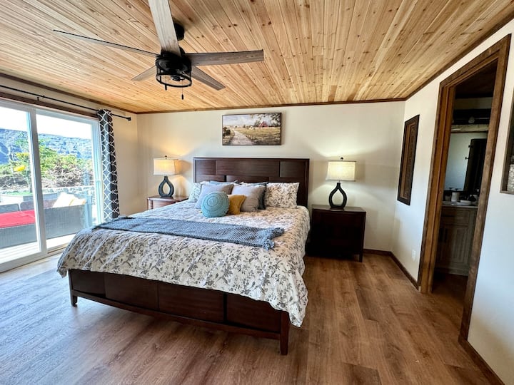 غرفة نوم رئيسية مع طاولات بجانب السرير ومصابيح وجميع الأرضيات الجديدة.