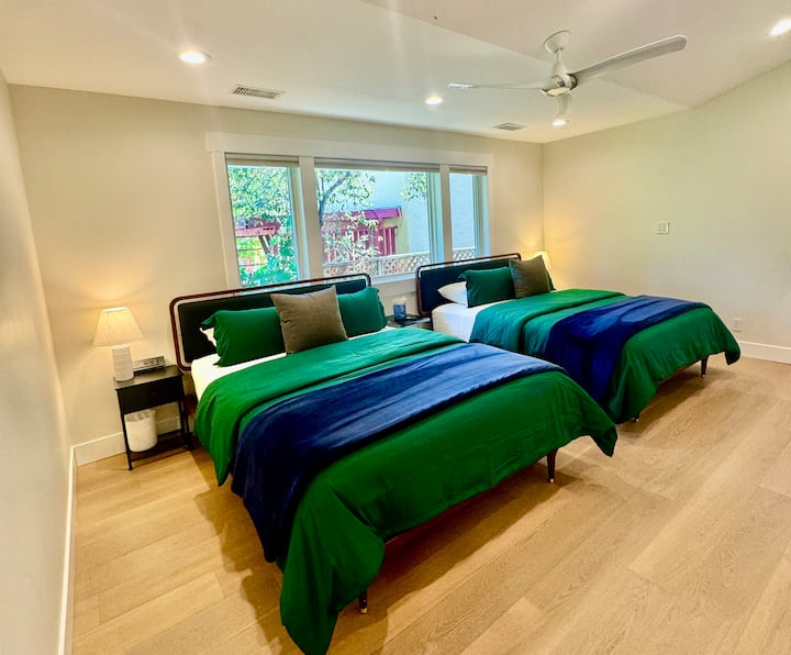 This bright and inviting room features two beds, soft lighting, and large windows that bring in natural light. Perfect for families or groups traveling together.