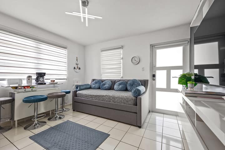 Comodidad y entretenimiento en la sala de estar con un televisor inteligente de 65 pulgadas, wifi, Netflix, Hulu, un sofá cama y un aire acondicionado. El espacio se combina a la perfección con una cocina bien equipada y una mesa de comedor ampliable con cuatro taburetes. 