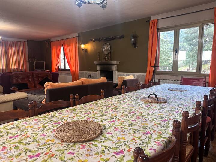 Comedor abierto al salón con mesa amplia y chimenea al fondo: espacioso y acogedor.