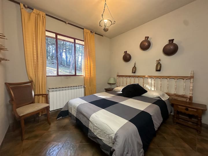 Dormitorio 2 con cama de matrimonio y butaca junto al ventanal: acogedor y luminoso.