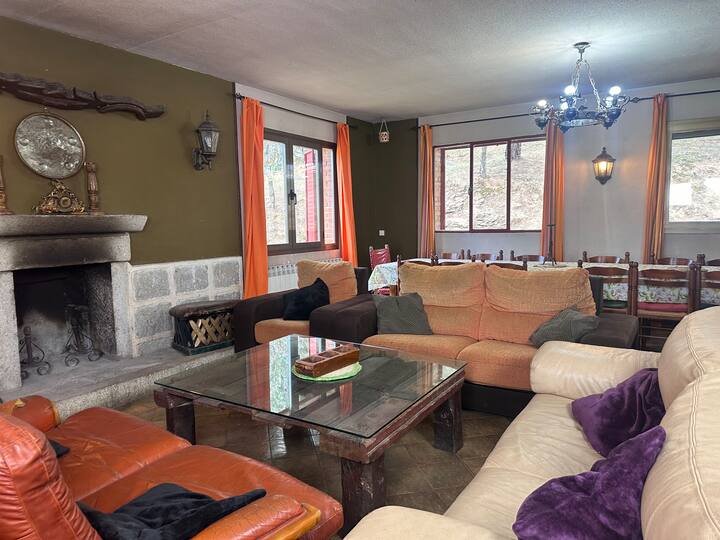 Salón con chimenea de piedra y sofás amplios: el punto de encuentro de la casa.