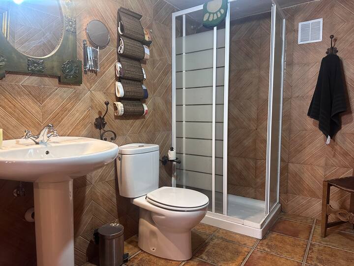 Baño completo 4 con lavabo, ducha e inodoro, alicatado en madera: acogedor y práctico.