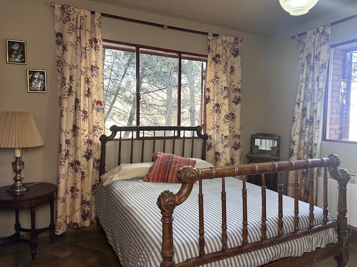 Dormitorio 1 con cama de matrimonio de forja y ventana al bosque: acogedor y luminoso.