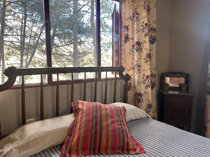 Dormitorio 1 con cama de forja junto al ventanal: vistas al bosque y ambiente tranquilo.
