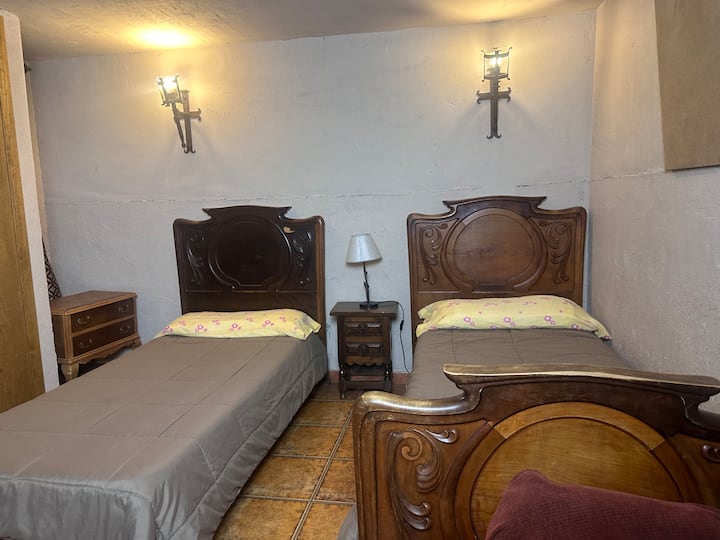 Dormitorio 6 con camas de forja y cabeceros de madera tallada: con mucho carácter.