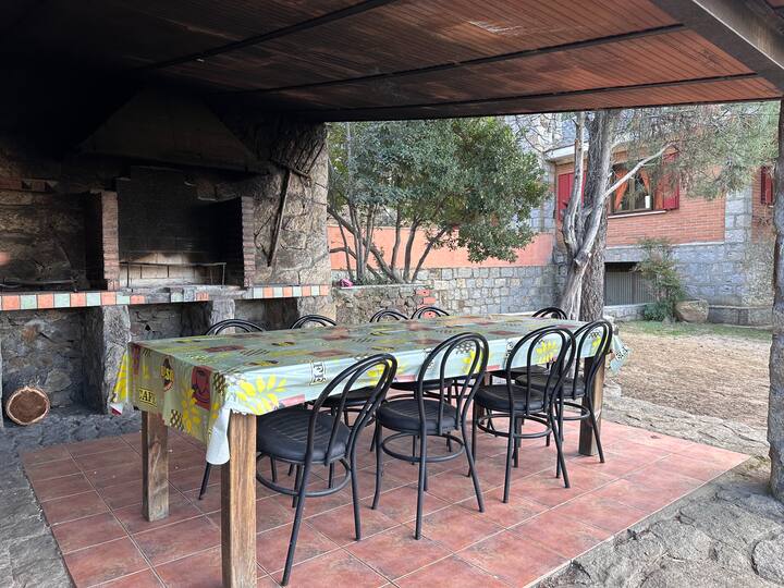 Merendero cubierto con barbacoa, mesa y sillas: perfecto para reuniones al aire libre.
