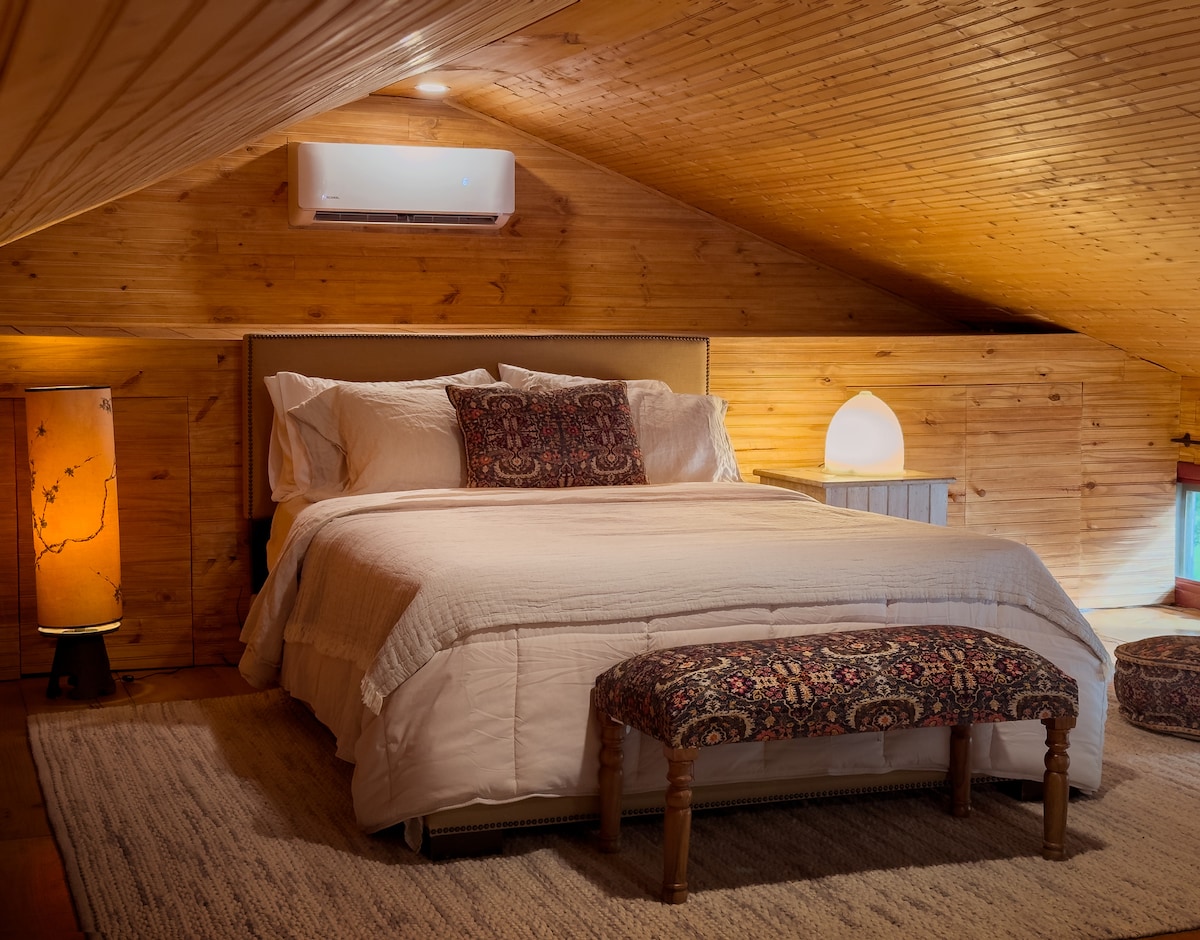 Este dormitorio loft (perfecto para cualquier persona menor de 5' 10")  es espacioso y acogedor con paneles de madera, un techo de pico bajo y vistas parciales al río. Nota: La habitación está abierta a la escalera desde la sala de estar, así como al loft para niños. 