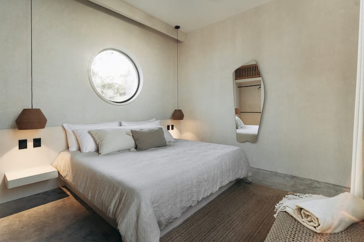 Uno de los cinco dormitorios con techos altos, 1
cama tamaño king grande con sábanas, persianas oscuras. Aire acondicionado, mucho espacio en el armario, seguridad personal y magníficas vistas a la selva.

Las ventanas circulares son un motivo de la villa.