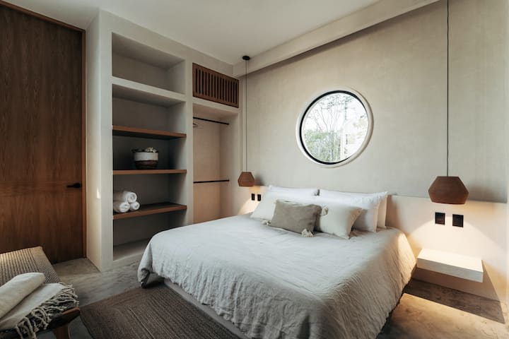Uno de los cinco dormitorios con techos altos, 1
cama tamaño king grande con sábanas, persianas oscuras. Aire acondicionado, mucho espacio en el armario, seguridad personal y magníficas vistas a la selva.

Las ventanas circulares son un motivo de la villa.