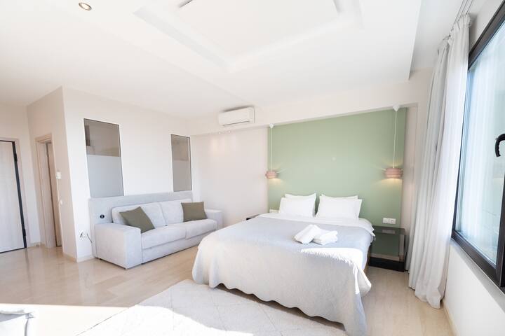 Suite luminosa y espaciosa con diseño moderno, cómoda cama doble y sofá. Un espacio ideal para relajarse, con tonos suaves y luz natural que crea una sensación de tranquilidad y comodidad.