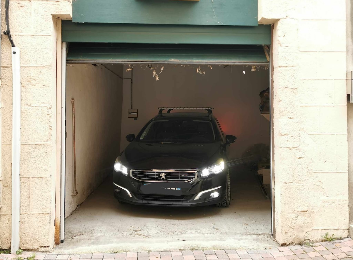 A spacious garage is shown, featuring a black vehicle parked inside. The garage door is partially open, revealing a clean concrete floor and bare walls. There is ample space for additional items or storage within the garage.