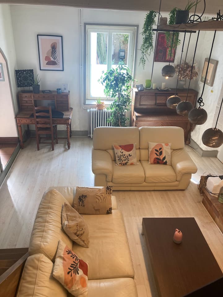 חדר מרווח שטוף באור, עם קישוט המשלב ריהוט וינטג' וריהוט עכשווי. ברקע יש פסנתר, צמחים ופינת עבודה, מושלמת לשהיות ארוכות יותר.