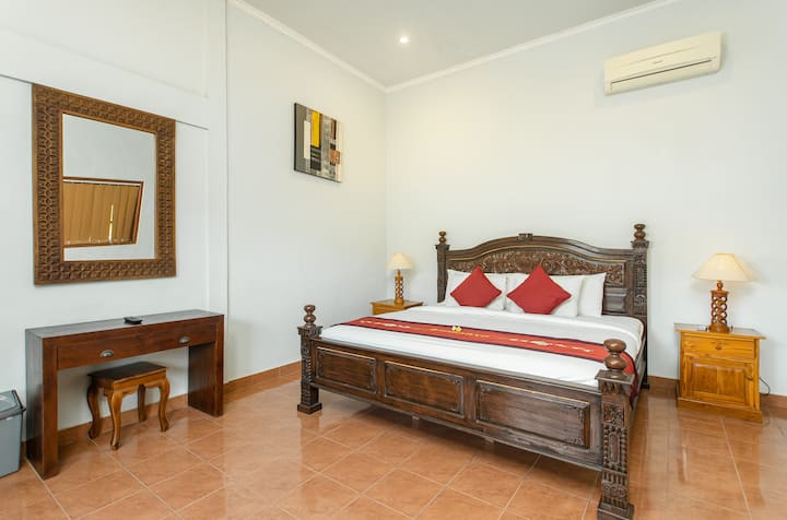 第三间卧室在楼上，提供超大号床（ 200 x 200厘米）、空调、干净的白色瓷砖地板、带灯的床头柜、带椅子的木桌和梳妆镜。