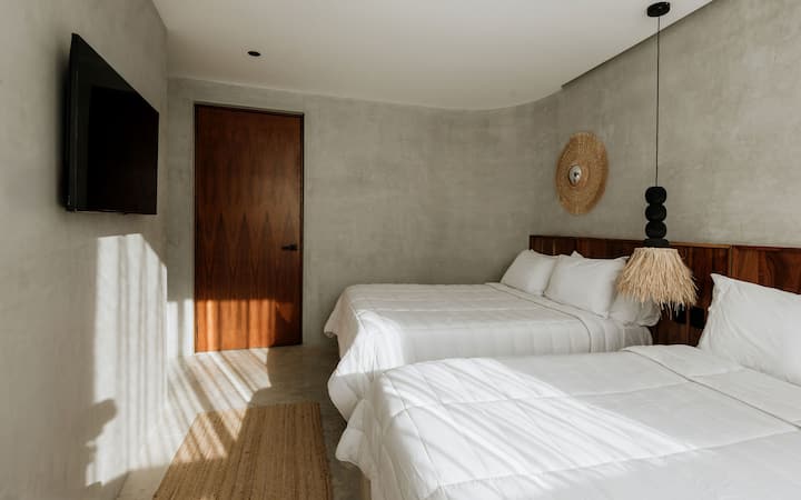 Two queen beds in a bright, inviting room with a peaceful pool view, a flat-screen TV, and a private ensuite bathroom for added comfort and convenience.