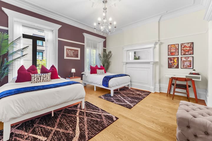 غرفة ضيوف واسعة مع سريرين صغيرين ولوحة ألوان جريئة توفر الراحة والشخصية.