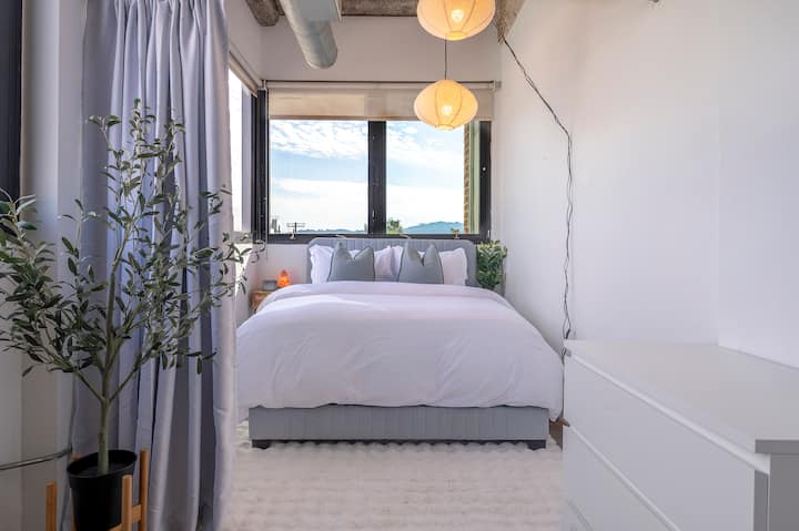 入住这张超舒适的标准双人床，配有柔软的白色床上用品和毛绒枕头，地理位置优越，沉浸在令人惊叹的晨光下。 这个空间采用柔和的照明、蓬松的地毯和绿色的气息，专为终极放松而设计。