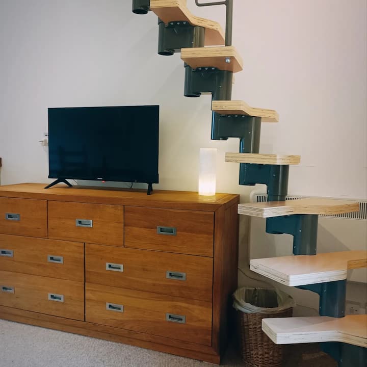 Living room space with fancy stairs up to the mezzanine.