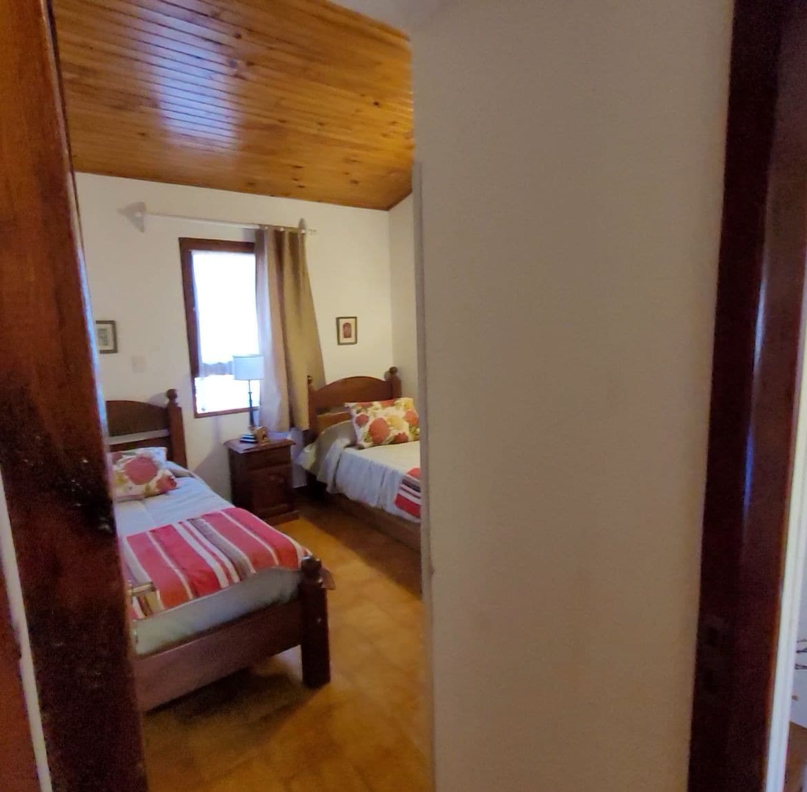 غرفة 3 بسريرين وبحار تحتها. تحتوي على طاولة خفيفة وحجاب ولافتة مع شماعات