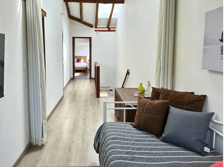 Espacioso corredor con techos altos y luz natural, ideal para descansar en el sofá cama o disfrutar de su diseño acogedor. Conecta con habitaciones cómodas, ofreciendo un ambiente relajante en Villa de Leyva.