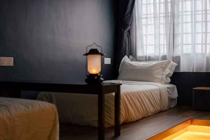 Sink into plush premium mattresses  from King Koil Luxury Hotel collection. Each bedroom comes fully air-conditioned with an attached bathroom. This common bedroom has an open clothes rack for hanging clothes.