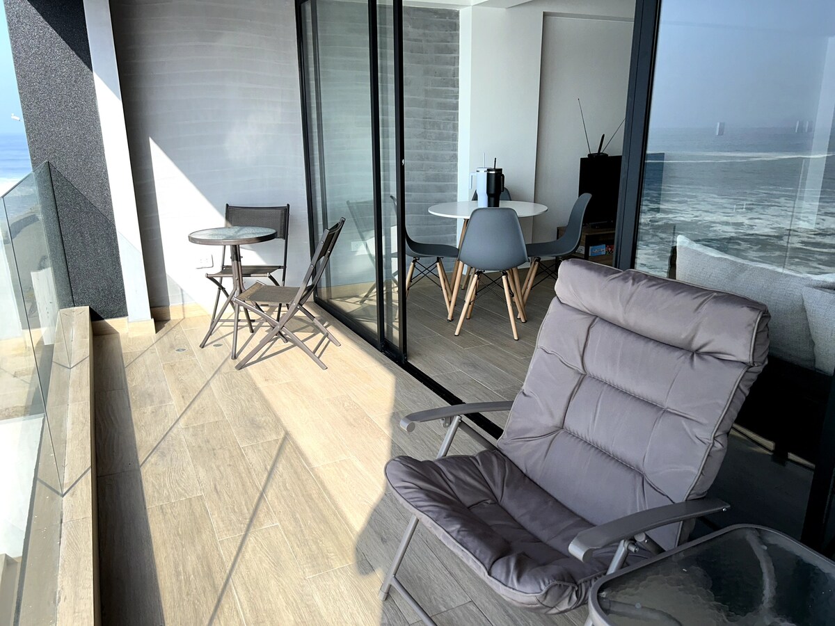 A spacious terrace features comfortable seating and a dining area with a round table. Glass walls provide unobstructed views of the surroundings, while modern furnishings complement the serene atmosphere. Natural light enhances the open space, creating a relaxing setting for enjoying the outdoors.