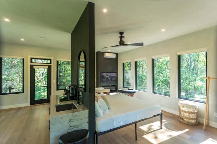 Luxury master bedroom with its king-sized bed, lime-washed walls,  wet bar, automated curtains, and TV lounge area