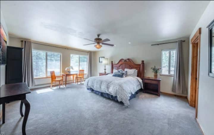 Amplio y soleado dormitorio principal con cama tamaño king, TV, mesa y sillas para una experiencia de desayuno en suite. También hay un gran vestidor.