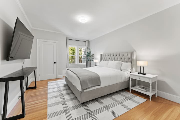 Relax in the master bedroom with a California king-size mattress, cozy blanket, and plush pillows. Enjoy adjustable lighting and a 65" TV mounted above a sleek console.