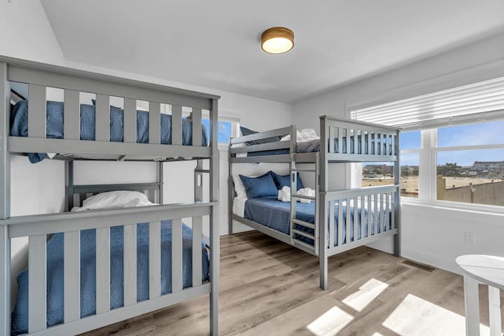 Dhomë gjumi me krevate dyshe dykatësh, ventilator tavani, shtroja blu dhe dysheme druri me dërrasa të gjera.